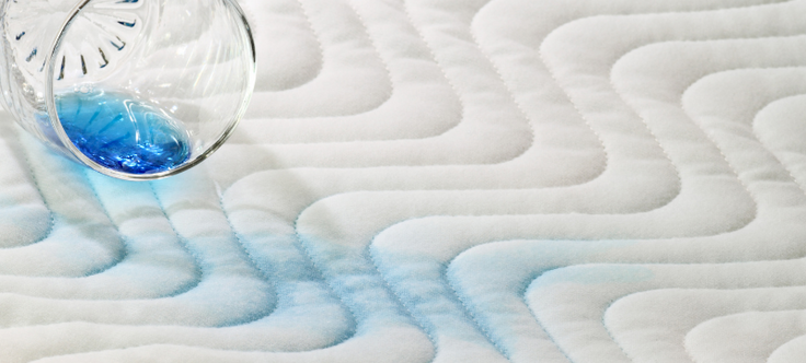 close up van incontinentiemateriaal met een omgevallen glas met blauwe vloeistof